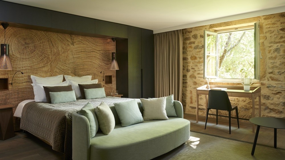 Contemporary French hotel bedroom with textured wooden wall, neutral bedding and elegant seating