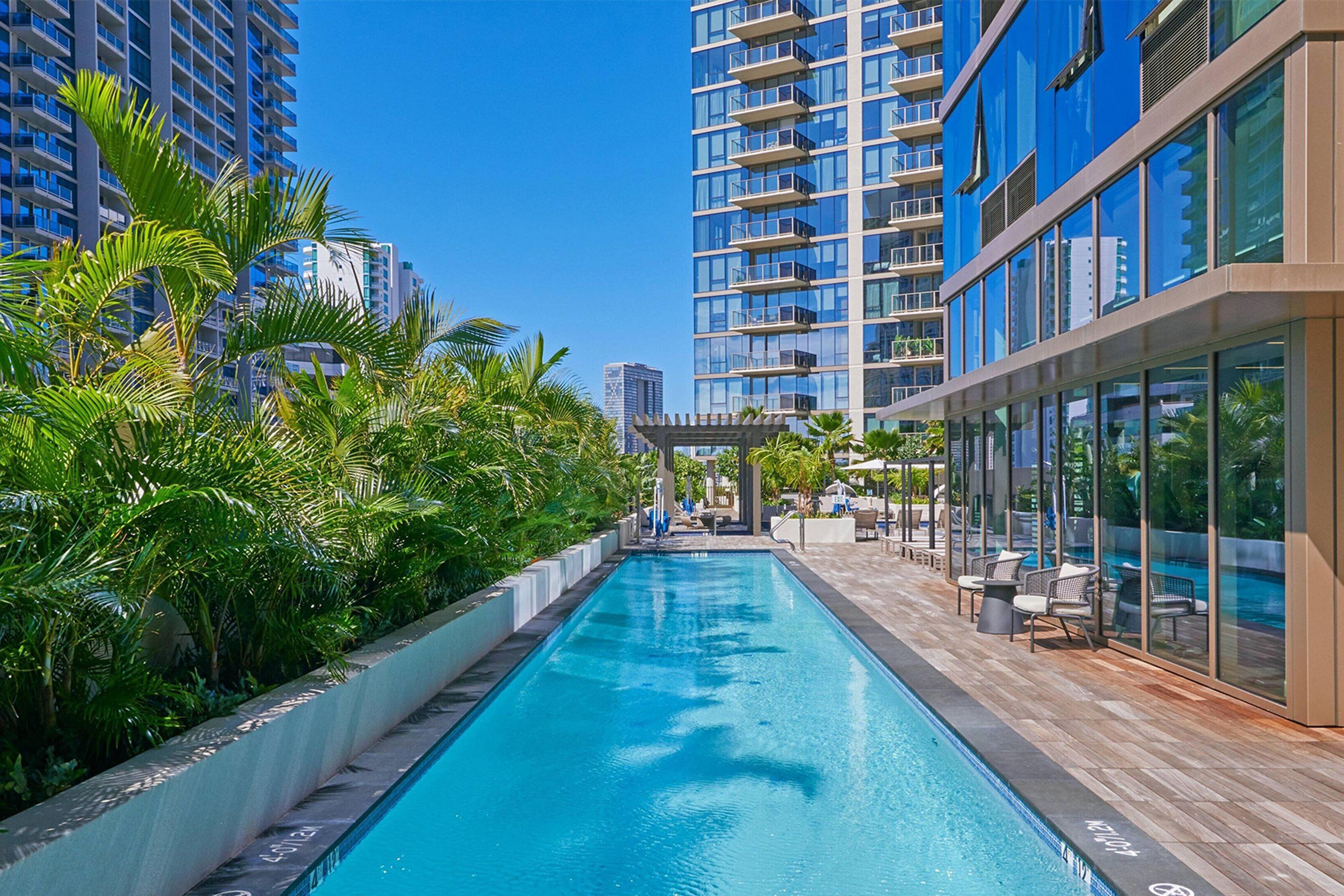 Elegant hotel with a sleek outdoor pool surrounded by lush greenery.