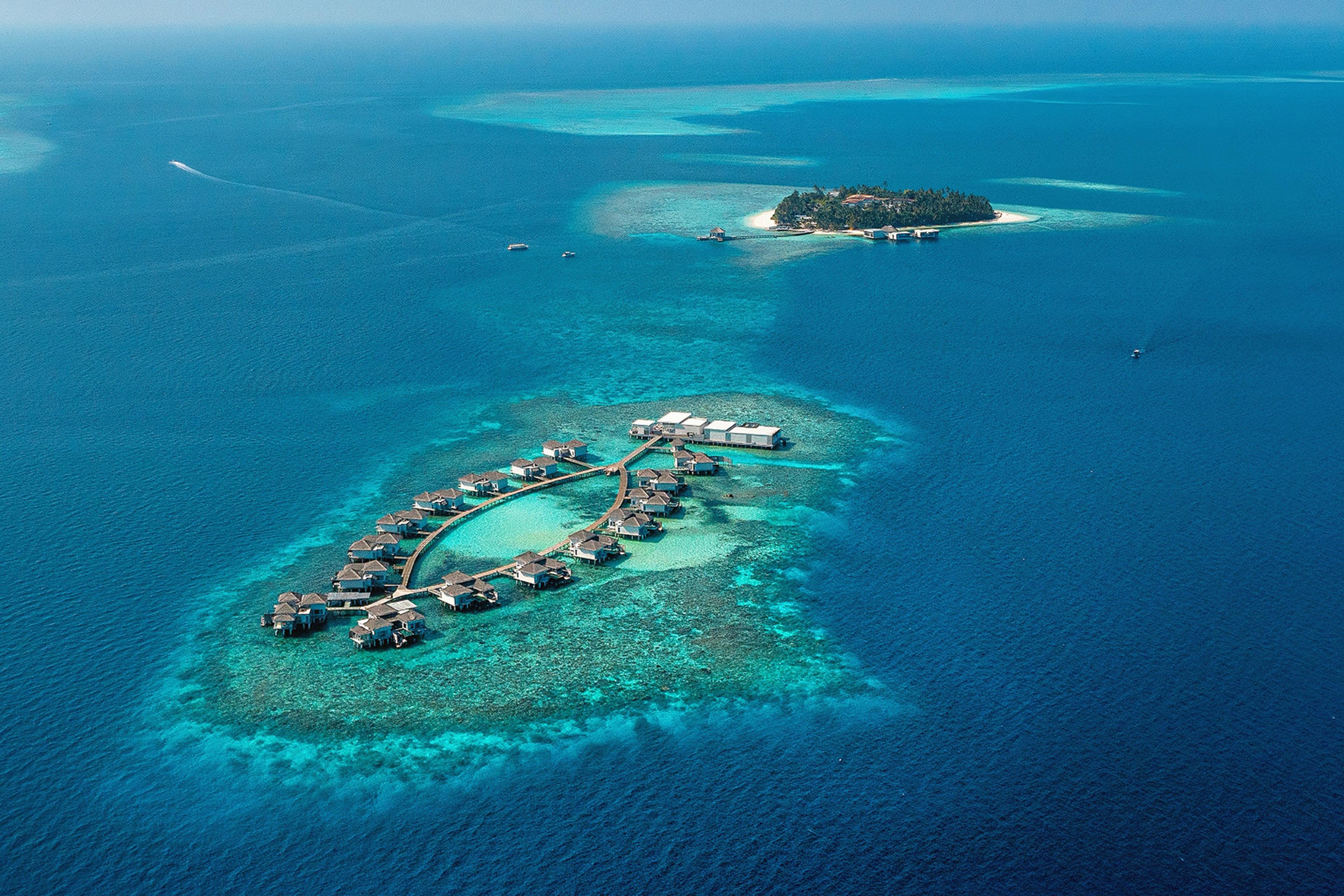 Overwater villas at Raffles Maldives Meradhoo surrounded by turquoise waters.