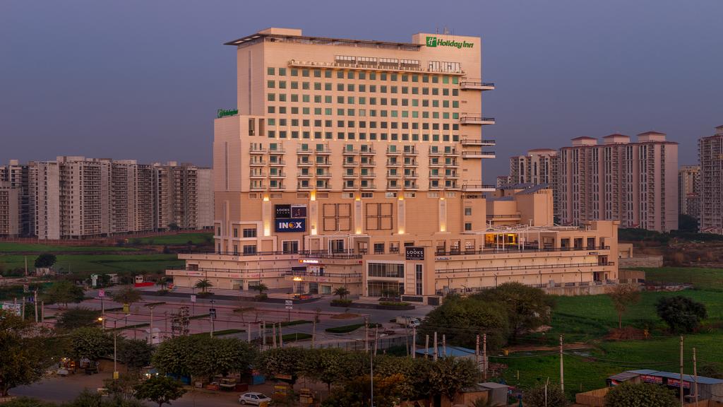 Exterior view of Holiday Inn Gurugram Sector 90 at dusk.