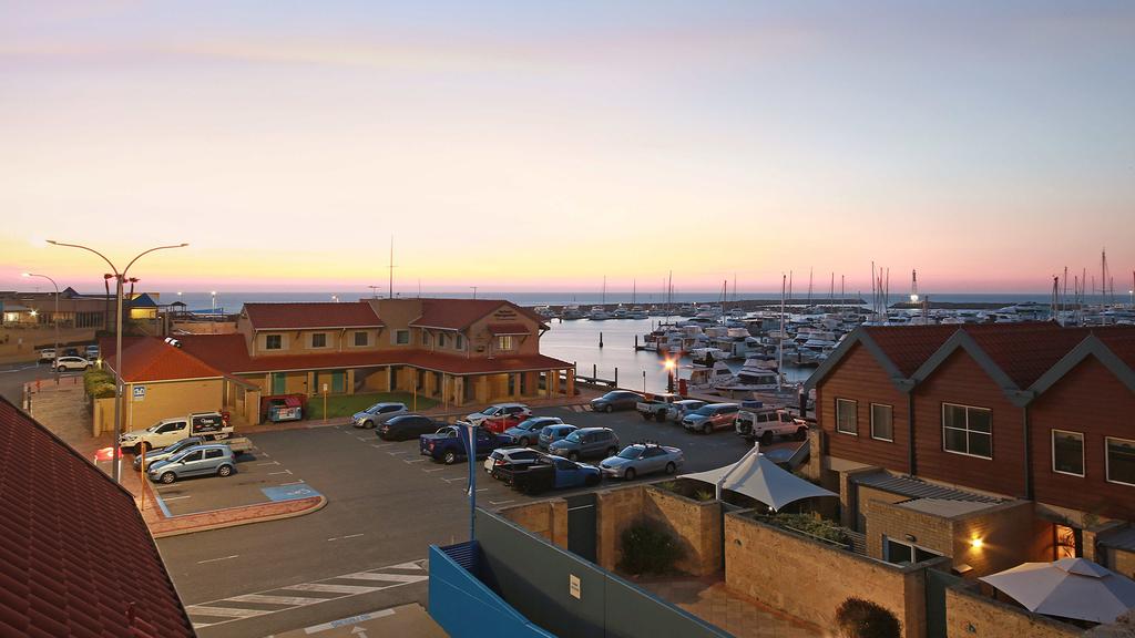 Hillarys boat harbour at sunset with parked cars and moored boats.