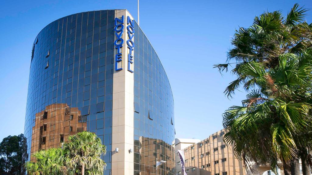 Exterior of Novotel Sydney Parramatta with palm trees in view.