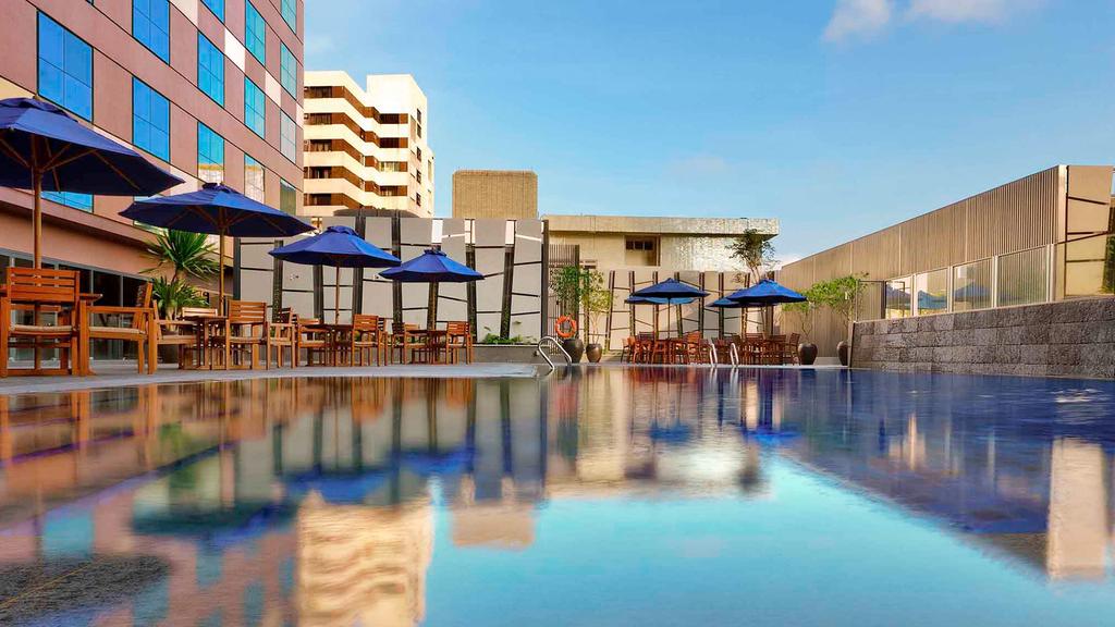 Outdoor pool area at Grand Mercure Singapore with seating and umbrellas.