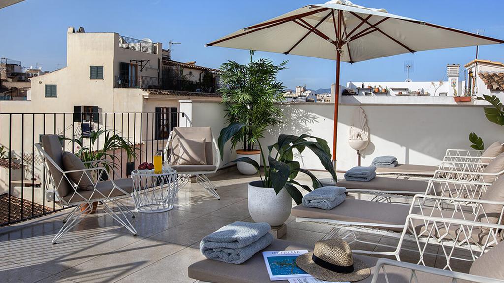 Rooftop terrace at Samaritana Suites with sun loungers and city views.
