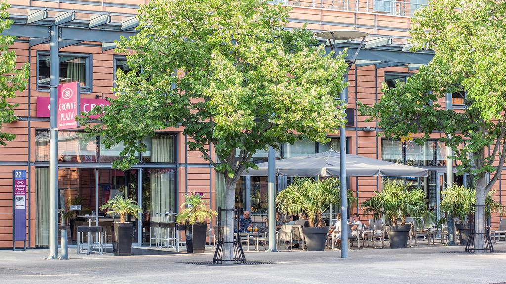 Crowne Plaza Lyon with outdoor seating surrounded by greenery.