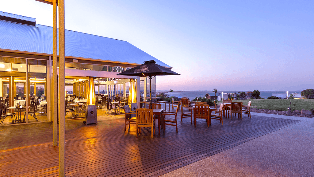 Outdoor dining area with ocean view at Silverwater Resort in San Remo at dusk. 