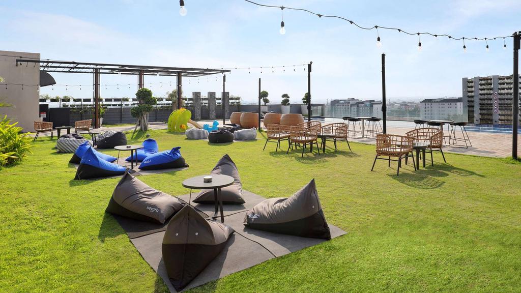Rooftop seating area with pool and city view at Novotel Yogyakarta.