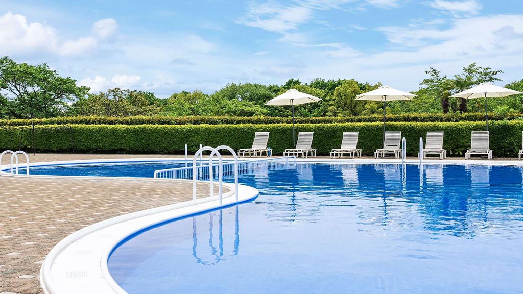 Outdoor pool surrounded by loungers and umbrellas at a Japanese resort.