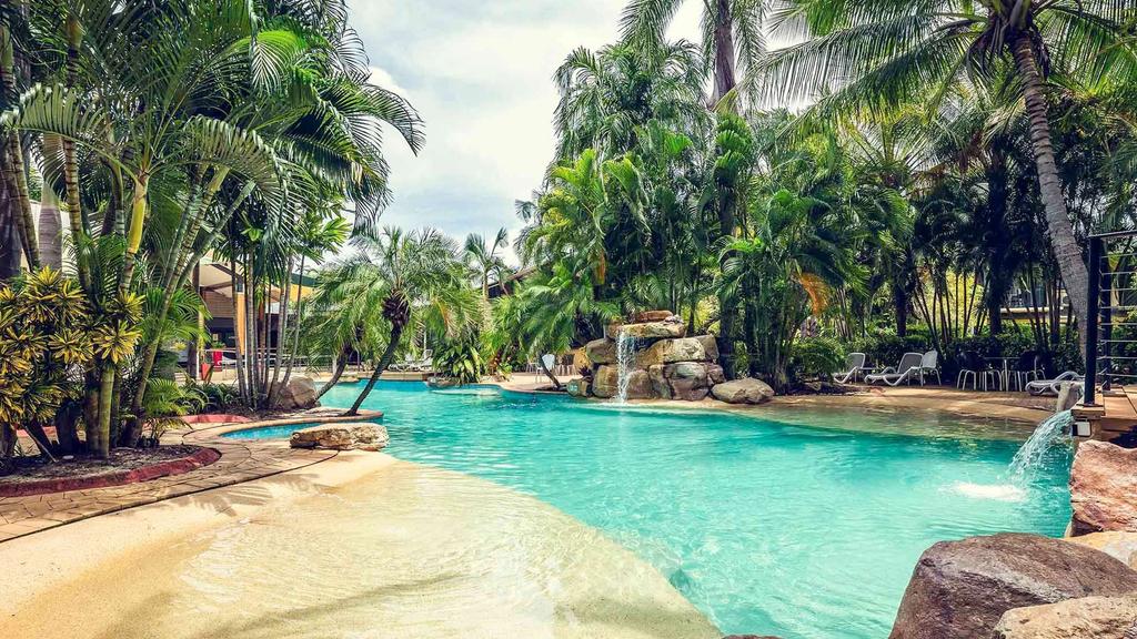 Tropical lagoon-style pool surrounded by lush greenery at a resort.