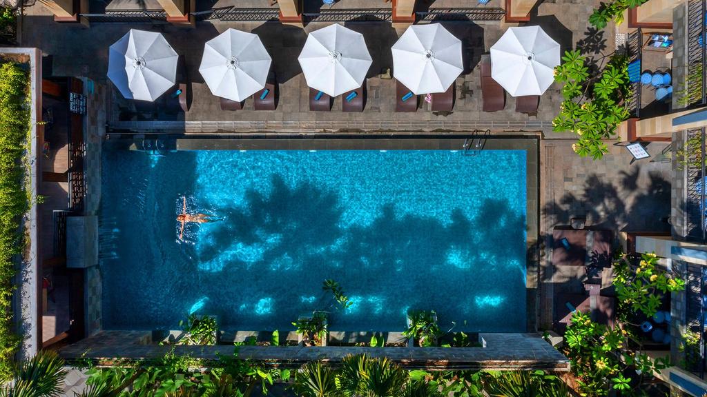 Solia Legian Bali with poolside loungers and vibrant greenery.