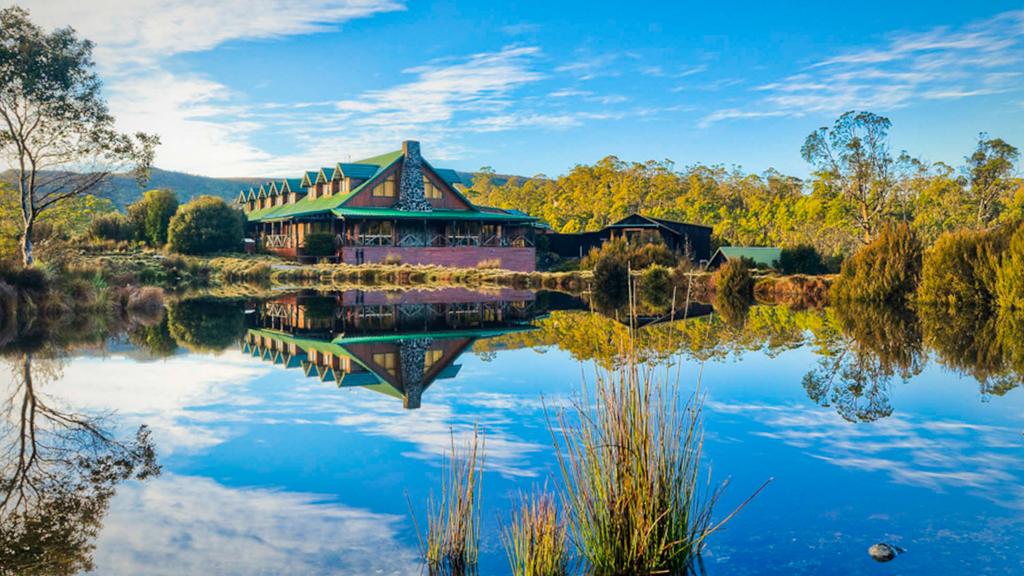 Reflective lake view of a rustic lodge surrounded by natural beauty.