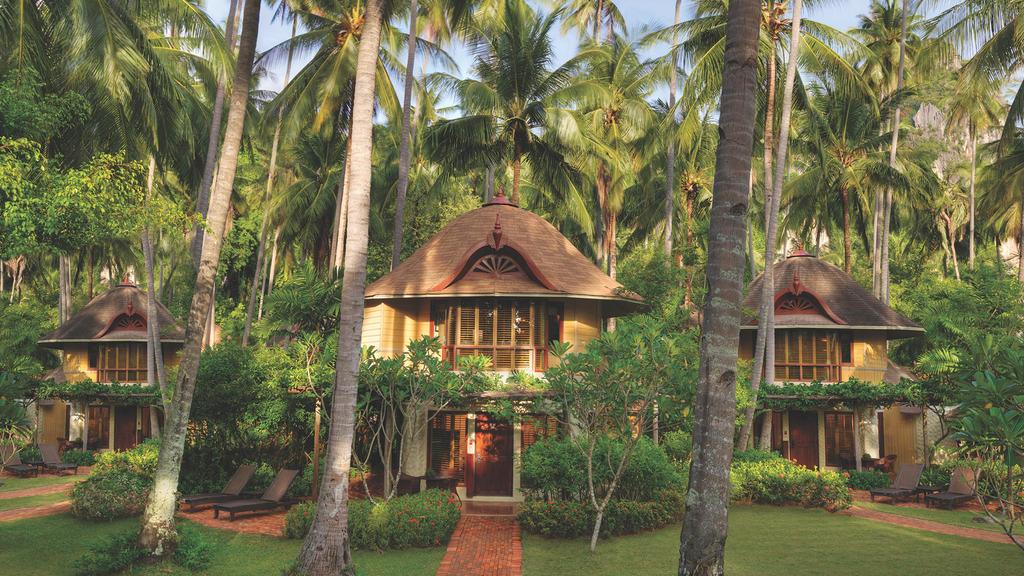 Thai-style resort pavilions surrounded by lush palm trees in Krabi.