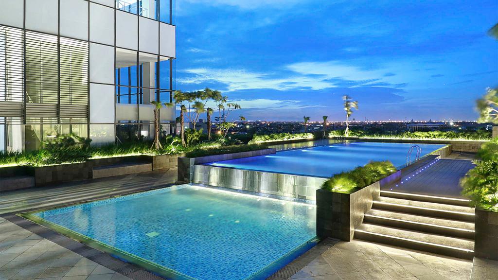 Modern hotel with illuminated outdoor pool at dusk in Surabaya.