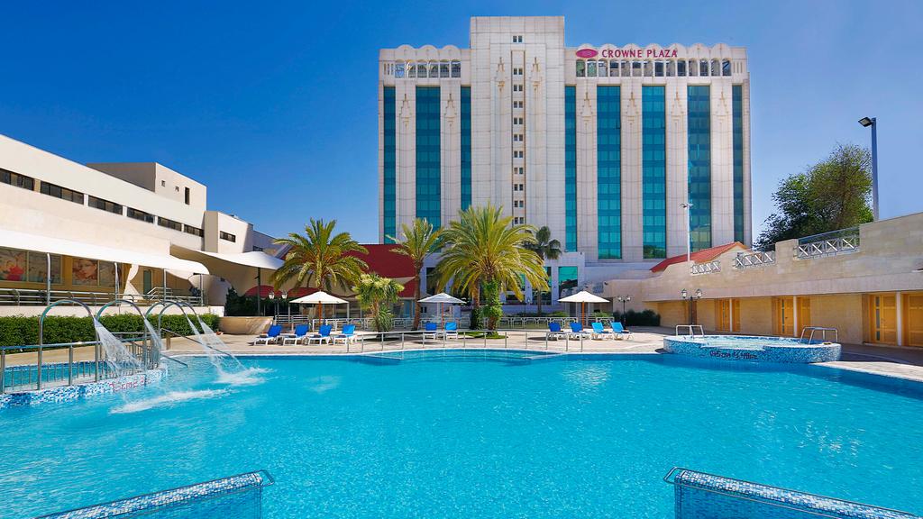 Crowne Plaza Amman with a sparkling outdoor pool and palm trees.