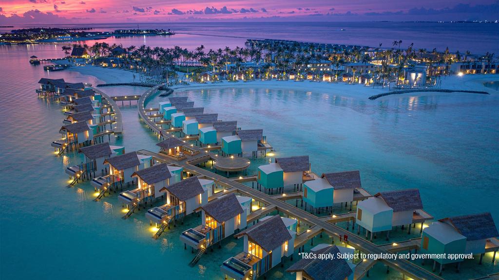 Aerial view of Hard Rock Maldives' overwater bungalows at sunset. 
