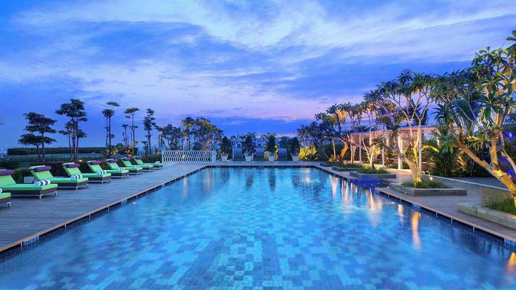 Rooftop garden pool at Novotel Tangerang with surrounding greenery at dusk.