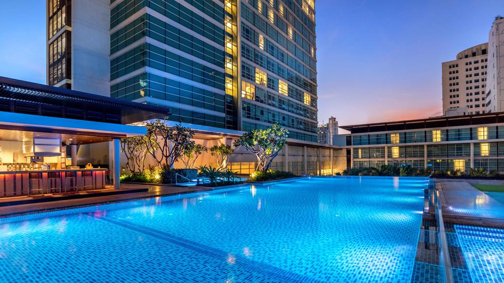 Luxurious rooftop pool at Pullman Bangkok with evening city view. 