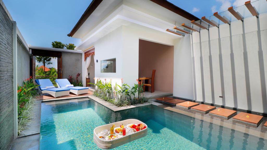 Private Deluxe One Bedroom Pool Villa in Seminyak with sun loungers and dining space.