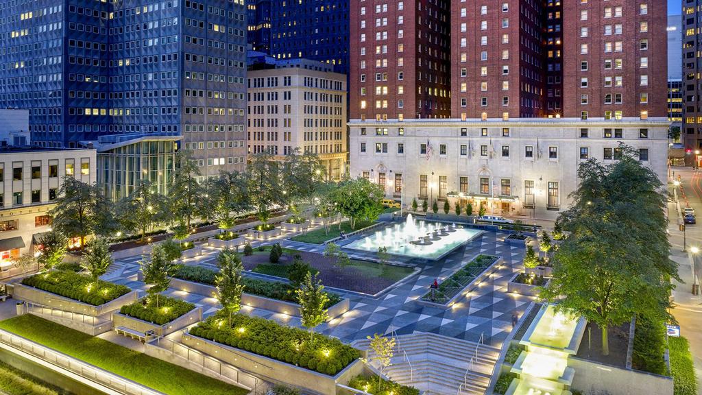 Grand heritage hotel in downtown Pittsburgh with lit fountains and gardens.