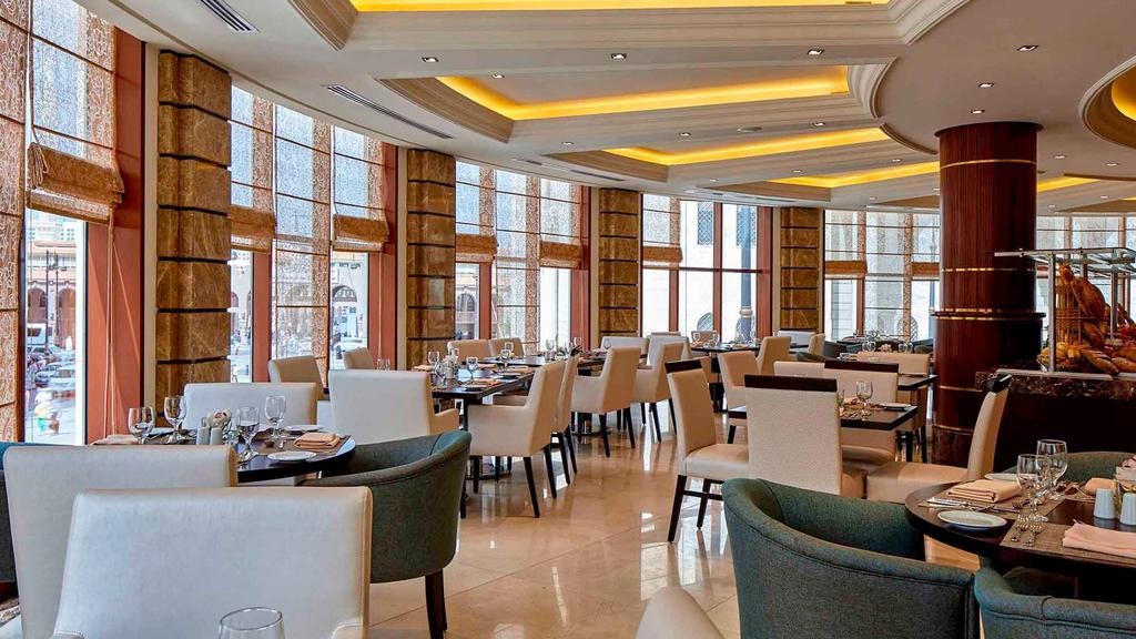 Elegant dining area at Pullman Madinah with large windows and plush seating.