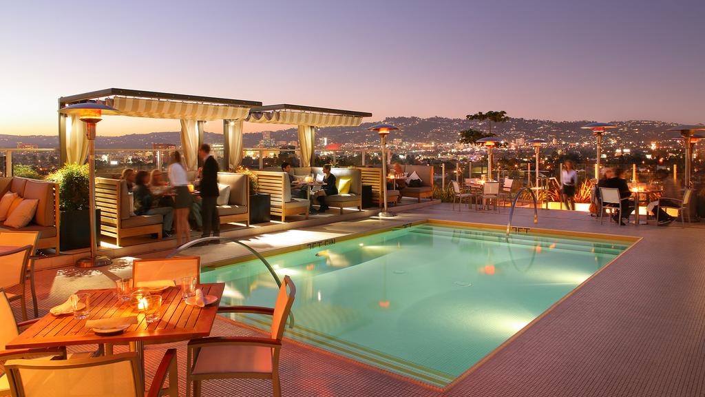 Rooftop pool and bar at night with views of the city skyline.