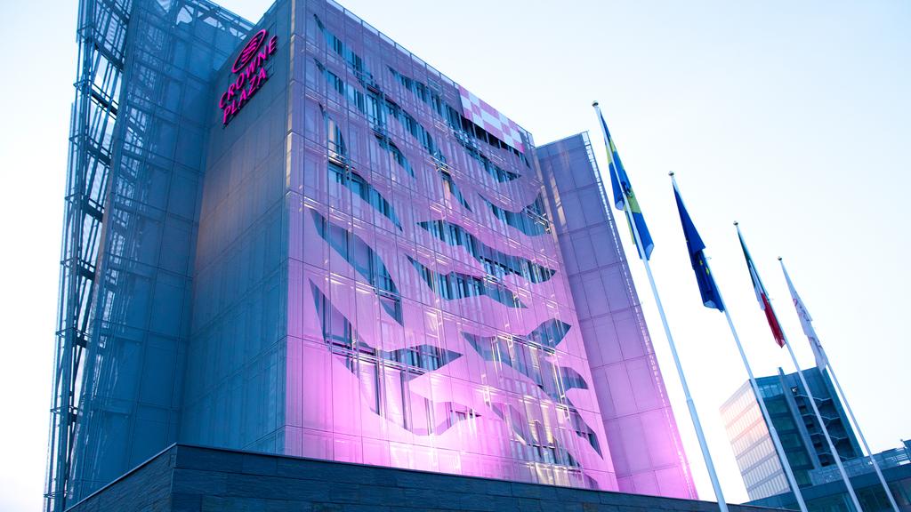 Crowne Plaza Verona illuminated exterior with flags displayed.