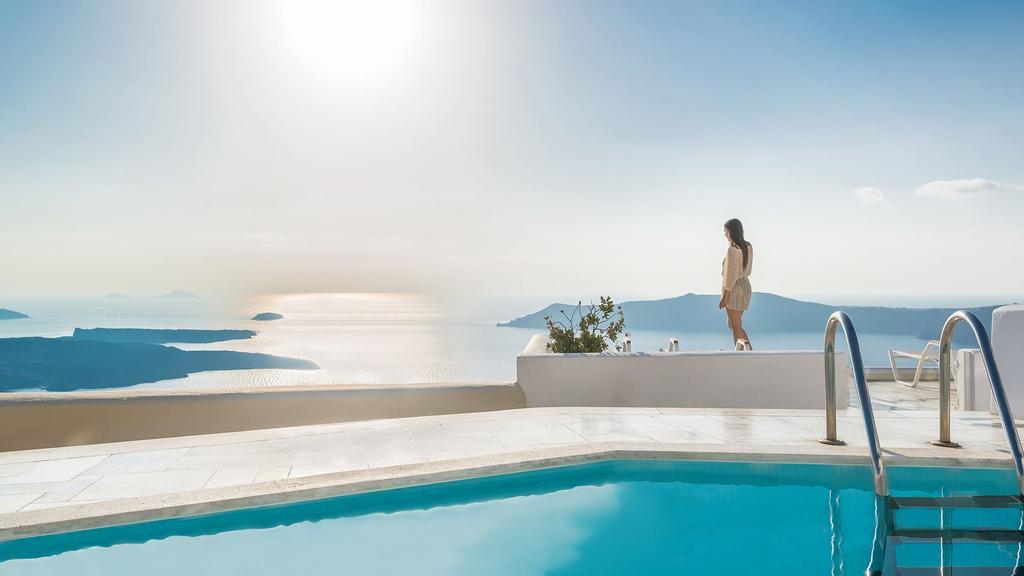 Woman enjoying ocean view from Santorini clifftop poolside at Iliovasilema Hotel & Suites.