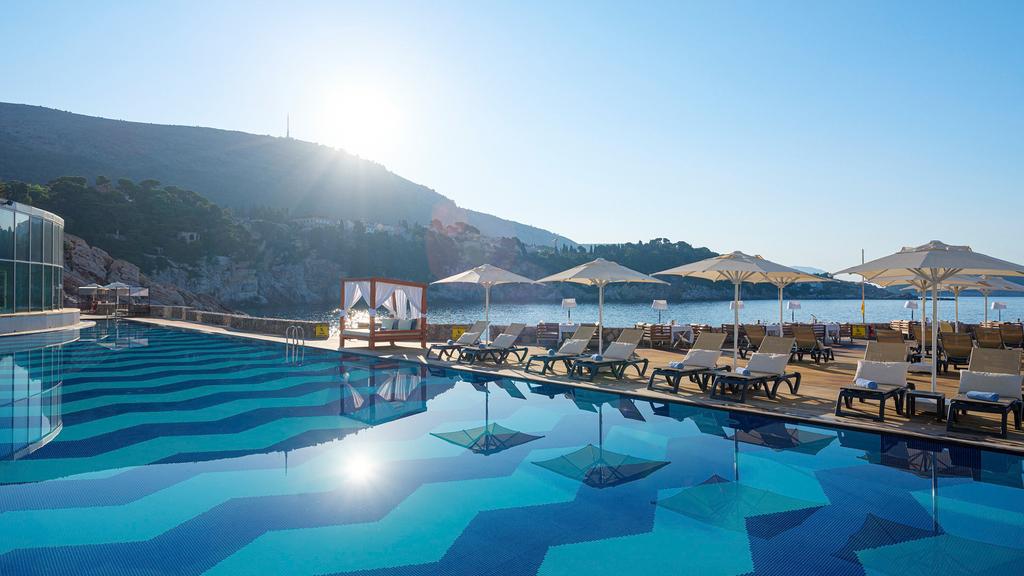 Sunlit poolside at a luxurious cliffside resort in Dubrovnik.