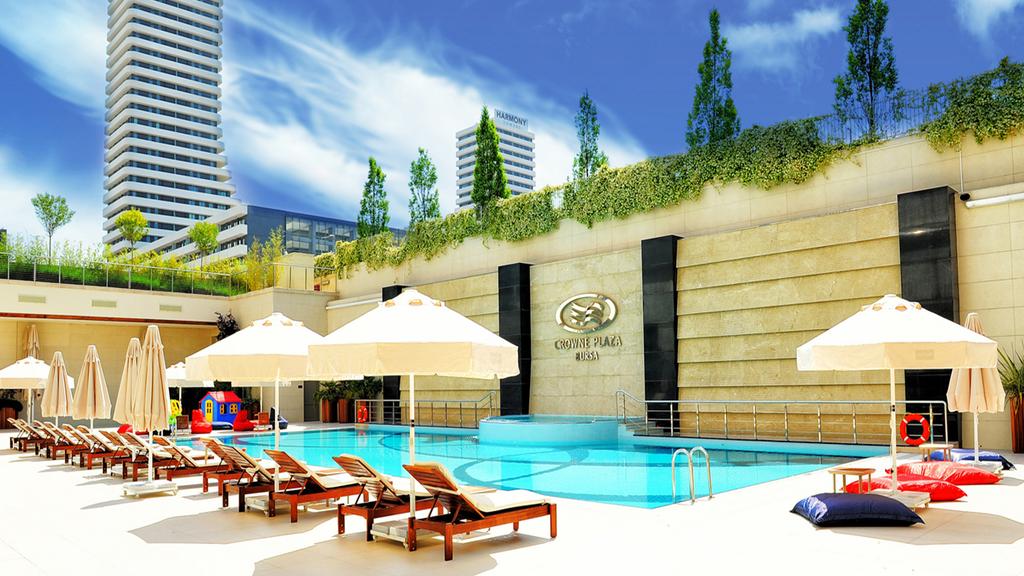 Outdoor pool area at Crowne Plaza Bursa with modern buildings in the background.