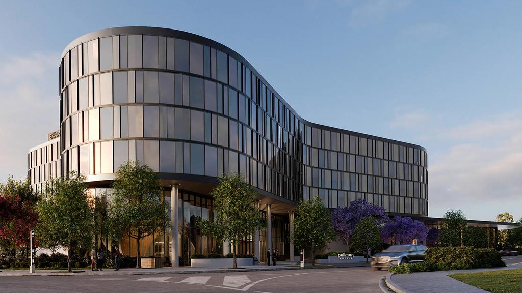 Modern facade of Pullman Sydney Penrith hotel with trees in foreground.