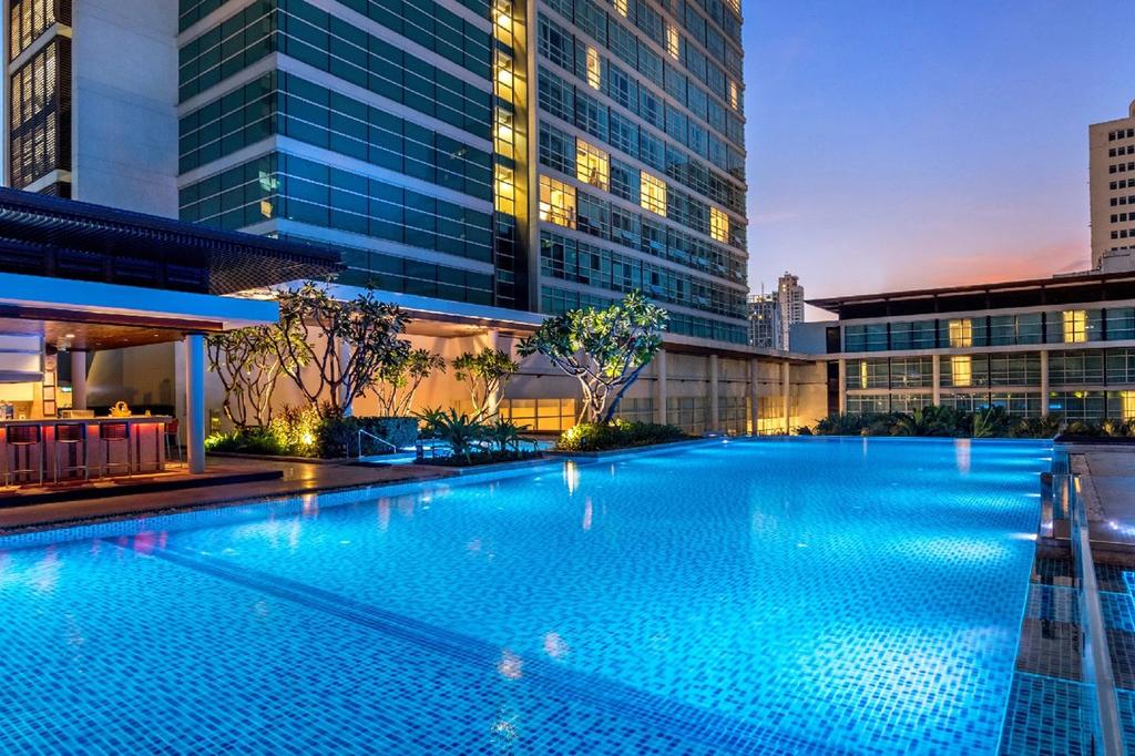 Luxurious rooftop pool at Pullman Bangkok with evening city view. 
