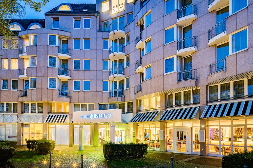 Facade of Hotel Indigo Dusseldorf with illuminated windows at dusk.