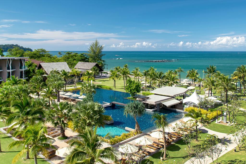 A beachfront resort with lush gardens and a large swimming pool.