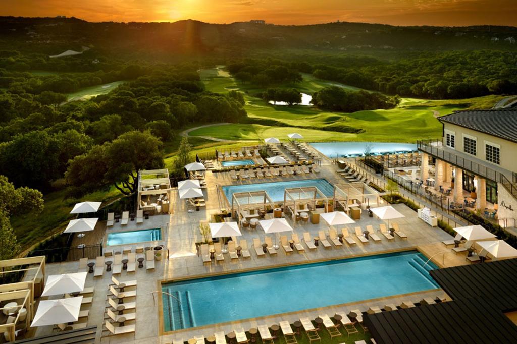 Aerial view of luxury resort with pools and golf courses at sunset.