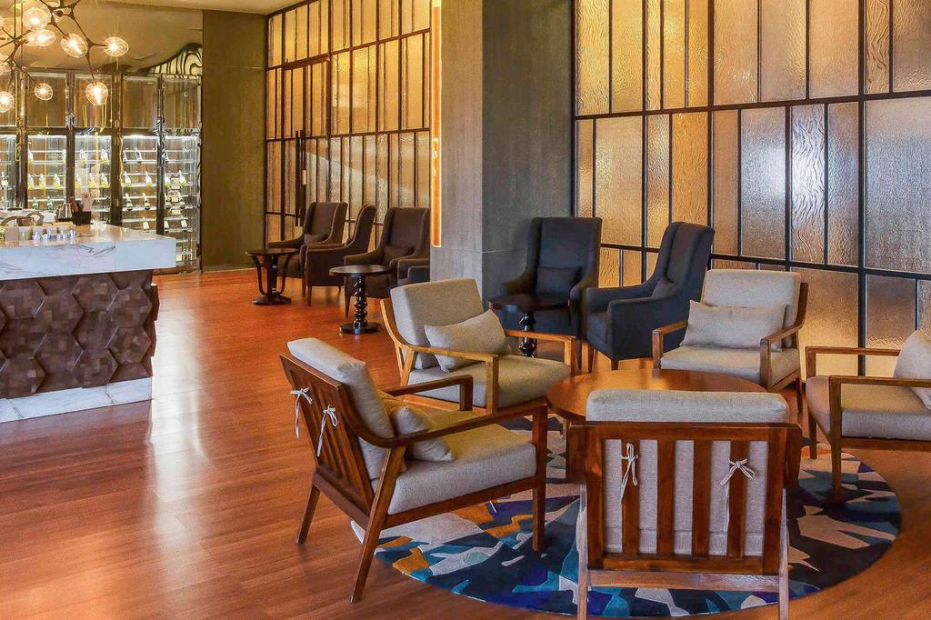Modern lounge area with stylish seating and a bar at Sumatran urban retreat.