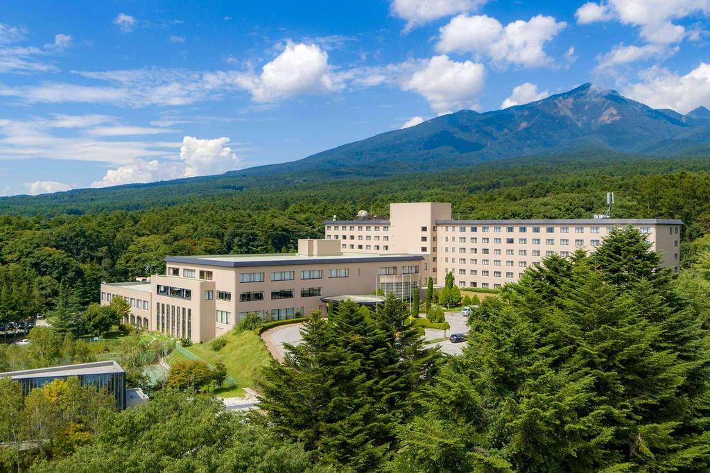 Hotel nestled at the base of Japan's Yatsugatake Mountains with forest views.