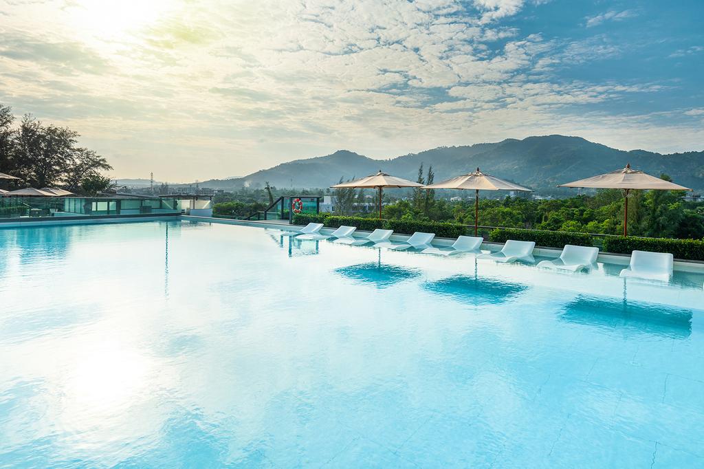 Phuket Hilton Garden Inn with Pool and lush green surroundings at sunset.