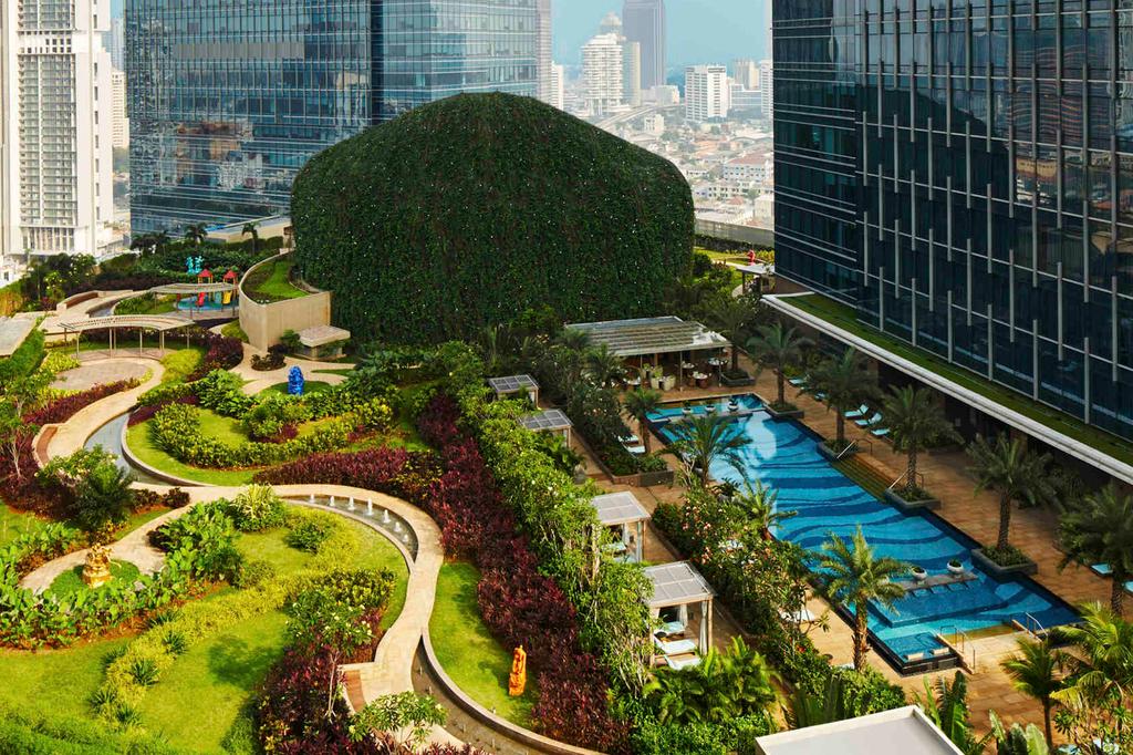 Aerial view of lush garden and pool at a luxury urban hotel.