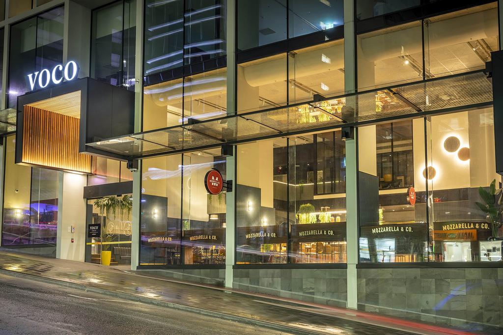 Exterior of voco Auckland City Centre hotel at night.