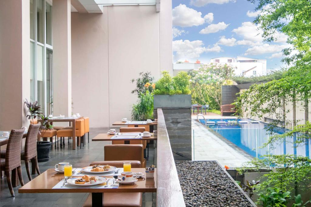 Outdoor dining area at Novotel Bandung with a view of the pool.