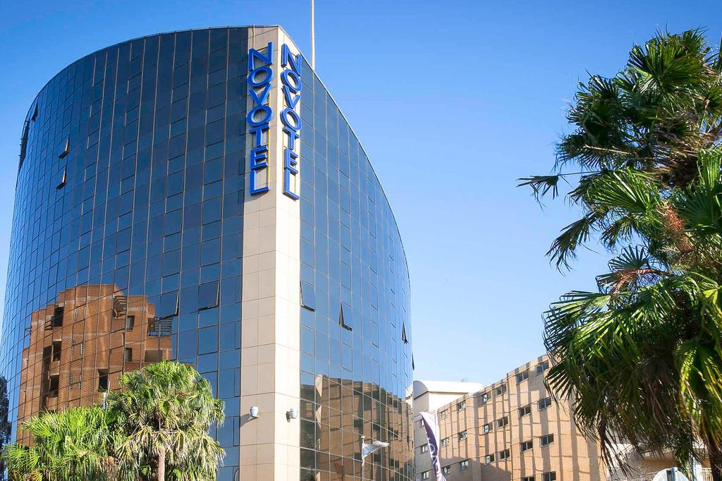 Exterior of Novotel Sydney Parramatta with palm trees in view.