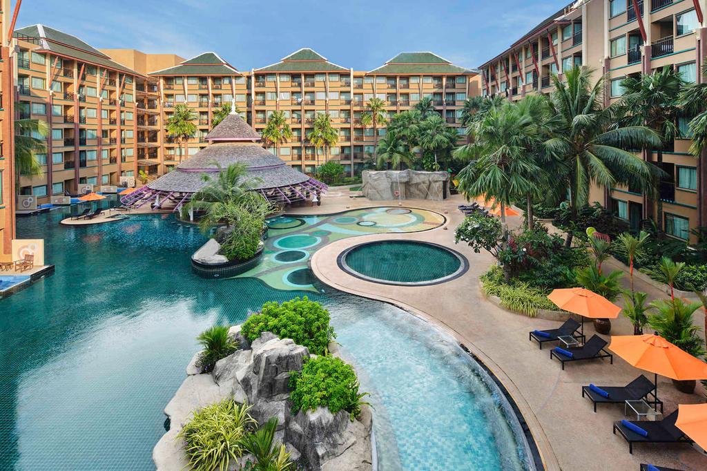 Expansive resort pool area with lounge chairs and lush greenery in Phuket.