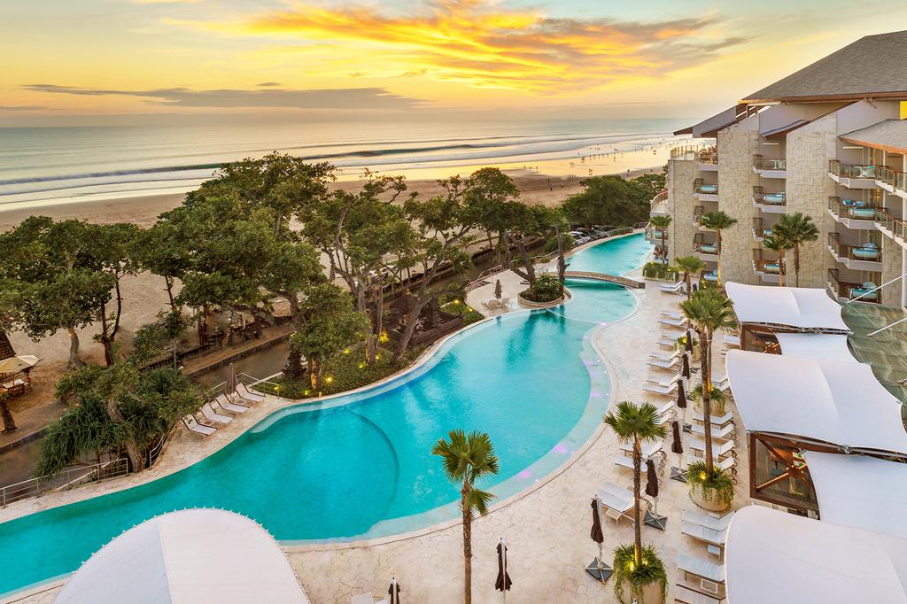 Infinity pool and beachfront view at Double-Six Luxury Hotel during sunset.