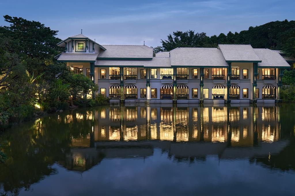 InterContinental Khao Yai Resort with lit windows reflecting on a tranquil lake.