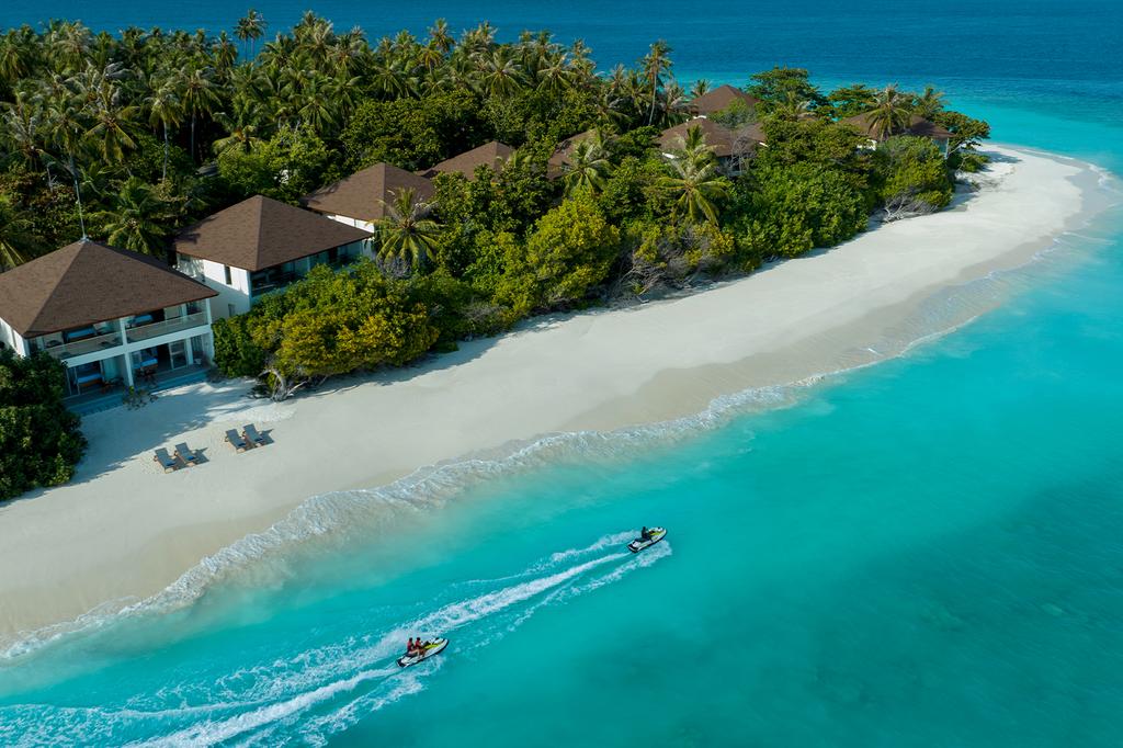 Aerial view of luxurious Maldives resort with pristine beach and lush palms.