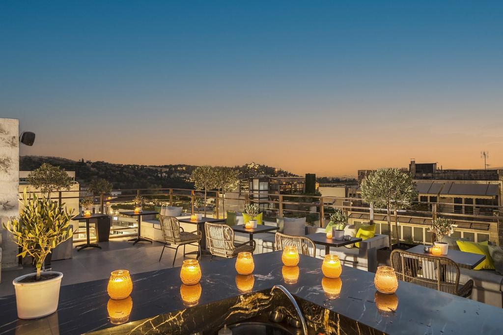Rooftop terrace with Acropolis views and candlelit ambiance at sunset.