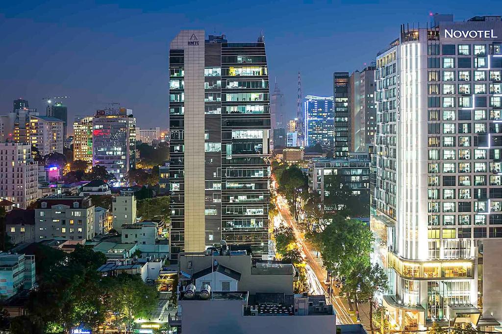Ho Chi Minh City skyline view with illuminated Novotel hotel at night.