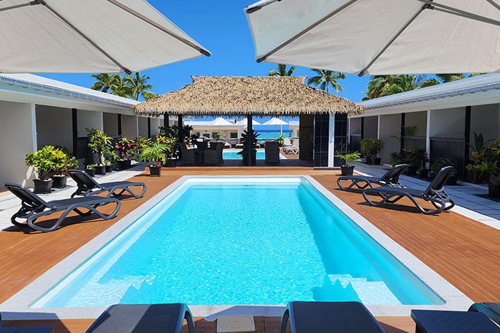 Luxurious resort pool area with sun loungers in Cook Islands seaside setting.