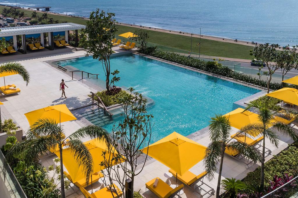 A luxurious poolside view at Shangri-La Colombo oceanside hotel with yellow umbrellas.