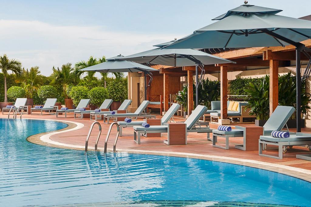 Outdoor pool with sun loungers at New World Saigon Hotel. 